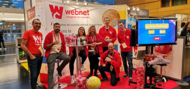 L'équipe de Webnet, prend la pose devant leur stand avec l'écran du jeu à côté