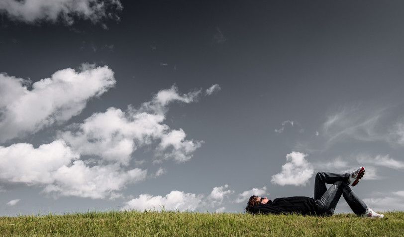 Homme allongé dans l'herbe qui regarde vers le ciel